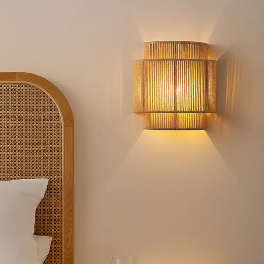Applique murale cylindrique en rotin tissé, style japonais, éclaire doucement.
