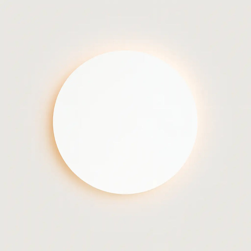 Applique murale LED ronde noire, design minimaliste, halo lumineux doux autour.