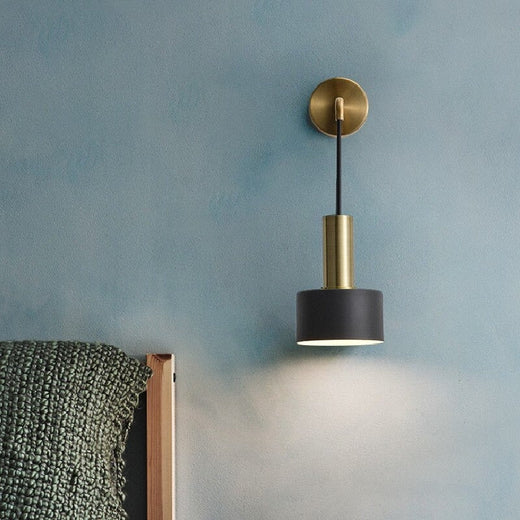 Applique murale design industriel doré et noire, éclaire élégamment un mur bleu contemporain.