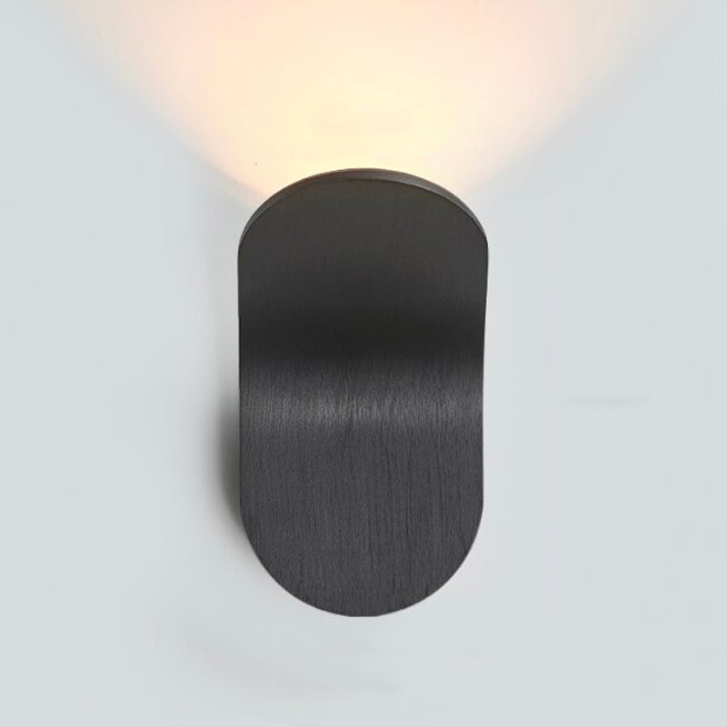 Applique murale ovale noire mate, diffuse une lumière LED chaude et minimaliste vers le haut.
