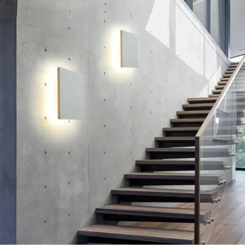 Deux appliques murales carrées en aluminium noir diffusent une lueur chaude et douce.